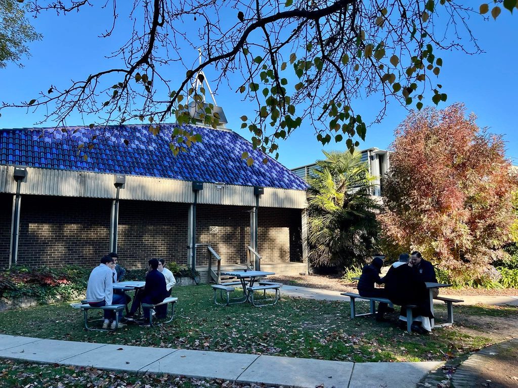 Students talking at picnic tables in the chapel courtyard in autumn